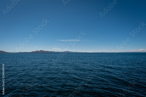 A view of enormous Lake Titicaca with a view the hills in the far distance on a clear and sunny day