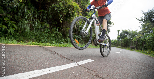 Woman cyclist riding mountain bike on tropical rainforest trail