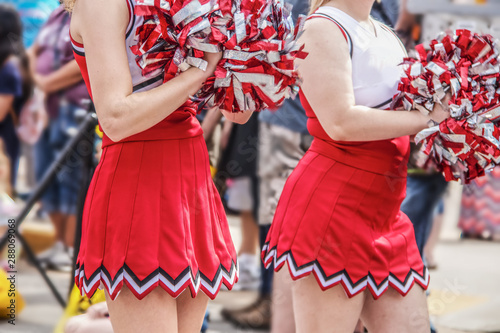 Obraz na płótnie High school cheerleaders with pompoms an shirt red and white uniforms in parade