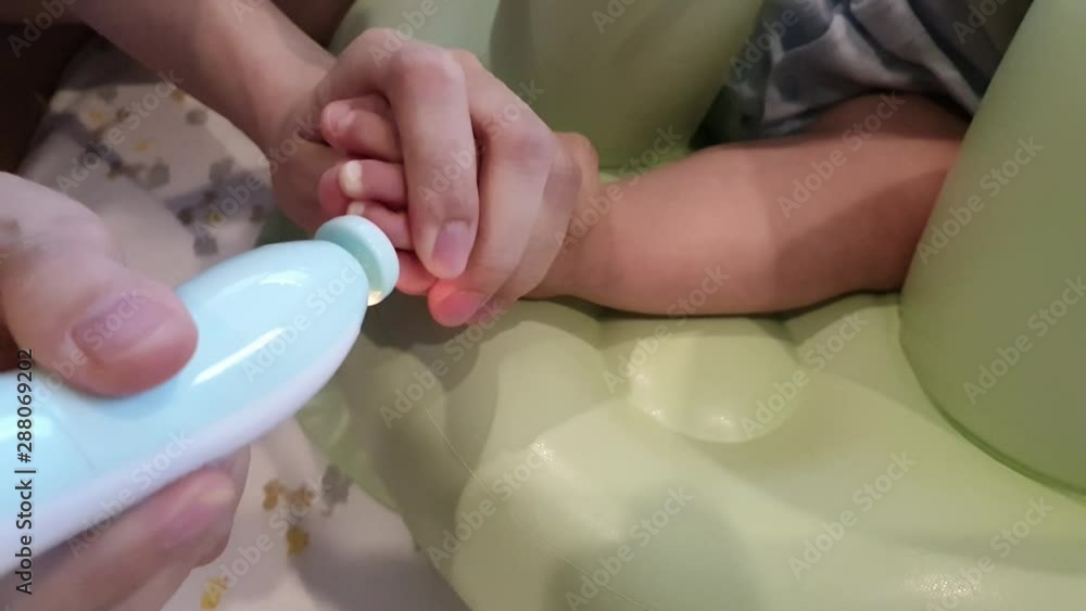 Mother is filling baby toe nails, difficult holding foot by her hand,using automatic file machine while baby movement is very convinience and easily triming by let's your baby take a seat. Mother is filling baby toe nails, difficult holding foot by her hand,using automatic file machine while baby movement is very convinience and easily triming by let's your baby take a seat.