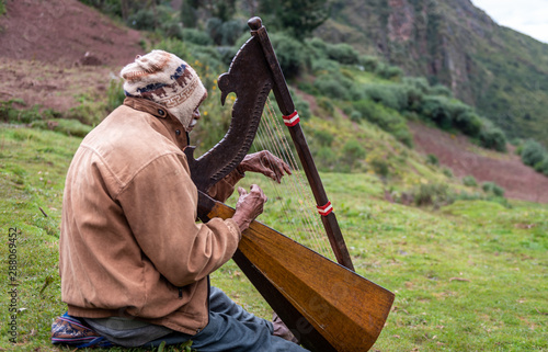 As the Peruvian man plays the harp on the mountain side, all the hikers flock to the incredible sounds he creates, echoing through the lush green valley on a cloudy day