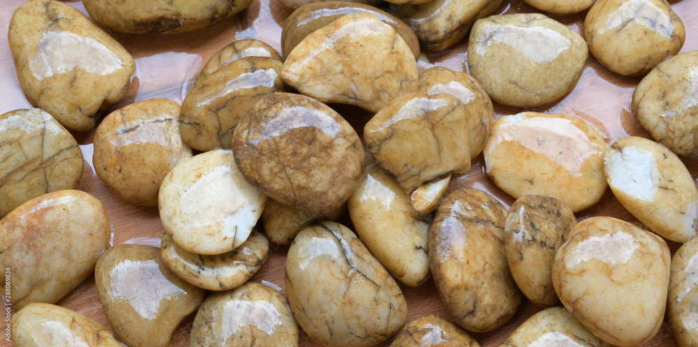 Close-up view of wet round brown pebbles on the ground Close-up view of wet round brown pebbles on the ground