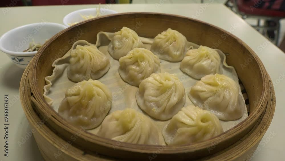 Chinese food, steamed hot “Xiaolongbao” in bamboo steaming basket. It is a type of Chinese steamed bun. Also known as dumplings, mantou and dim sum. Chinese food, steamed hot “Xiaolongbao” in bamboo steaming basket. It is a type of Chinese steamed bun. Also known as dumplings, mantou and dim sum.