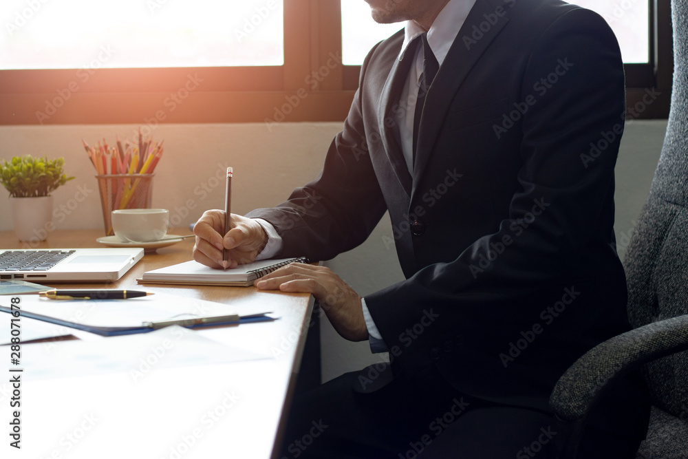Young business man working in bright office, using laptop, writing notes. Young business man working in bright office, using laptop, writing notes.