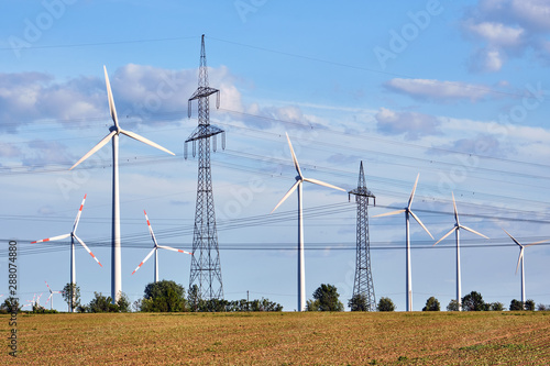 Tableau sur toile Wind turbines and power lines behind an acre seen in Germany