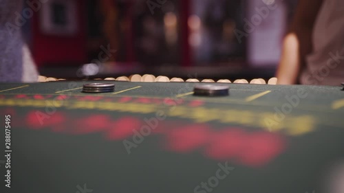 A man and a woman standing at a blackjack table waiting for their cards to be dealed out. Focus on the chips with a bokeh background. photo