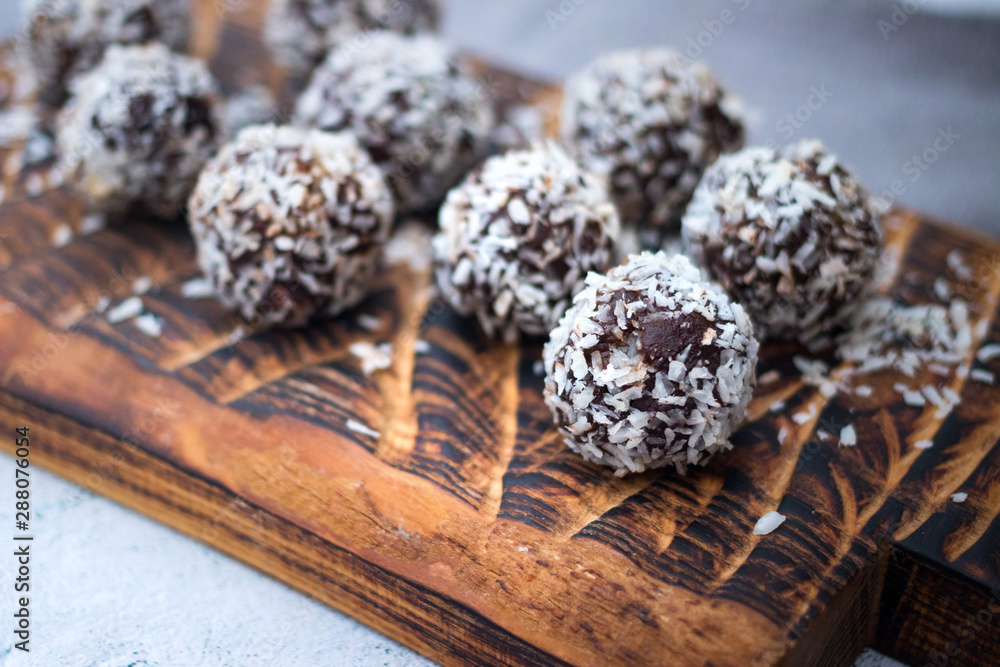Coconut sweet balls. Energy protein dessert with dates, cocoa, peanut butter on wooden board Coconut sweet balls. Energy protein dessert with dates, cocoa, peanut butter on wooden board