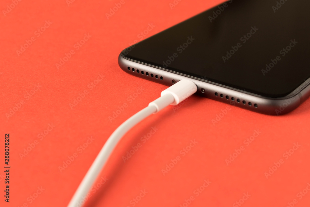 Smartphone on charge . On red background. Close up. Smartphone on charge . On red background. Close up.