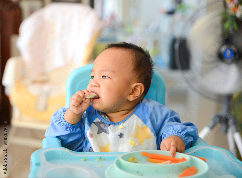 Asian baby boy 6 months old eating with Baby Led Weaning (BLW