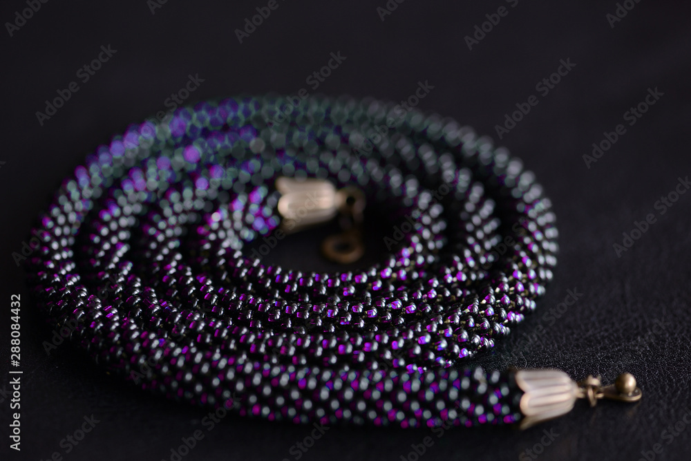Fototapeta premium Close-up of a long violet bead necklace on a dark background