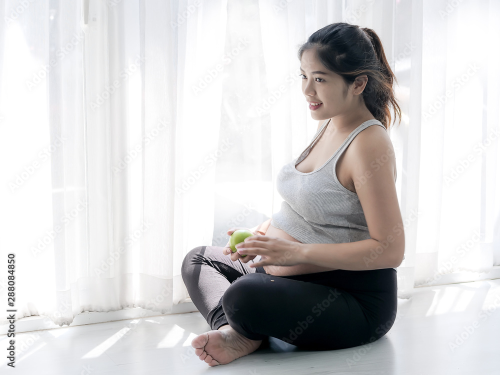 Happy Asian woma holding green apple in her hand and sitting on floor near window, lifestyle concept. Happy Asian woma holding green apple in her hand and sitting on floor near window, lifestyle concept.