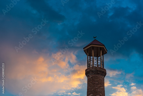 Minaret of an old mosque against the sunset sky