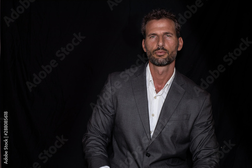 Green-eyed, handsome and sexy  businessman posing with jacket and shirt and black background