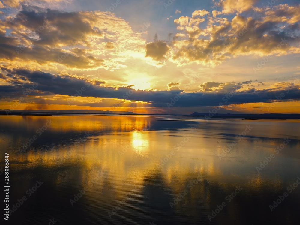 Obraz premium Aerial view, Beautiful Orange and red dramatic colors of sunset and cirrus clouds above the sea. Sky blue and orange natural dawn composition over the sea, Warm colors reflect the water surface.