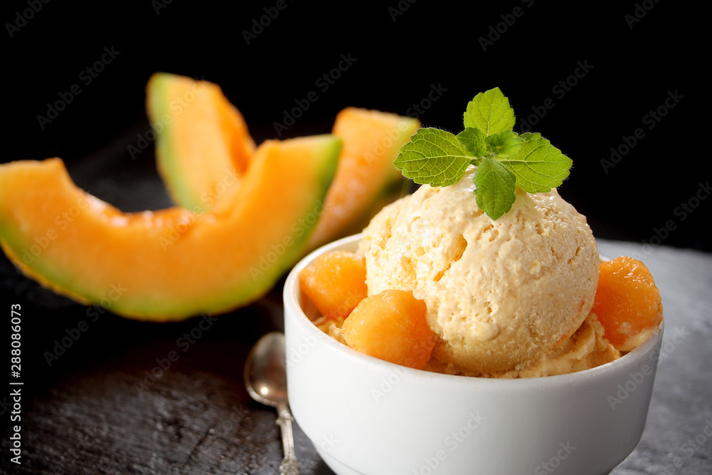 Fresh melon ice cream with melon and melissa on black background Fresh melon ice cream with melon and melissa on black background