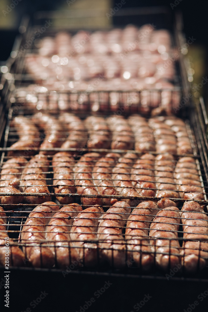 Close-up of delicious chicken or pork sausages on BBQ. Unrecognizable cook preparing tasty sausages on grill. Close-up of delicious chicken or pork sausages on BBQ. Unrecognizable cook preparing tasty sausages on grill.