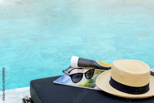 Book and hat on the sun bed near the swimming pool,