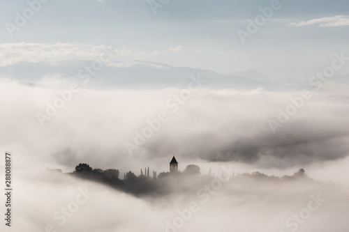 Surreal view of Mora town (Assisi) almost completely hidden by fog