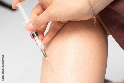 A close up view on the leg of a caucasian person as they insert a syringe needle filled with clear insulin into the skin, medical treatment for diabetic sufferer. photo