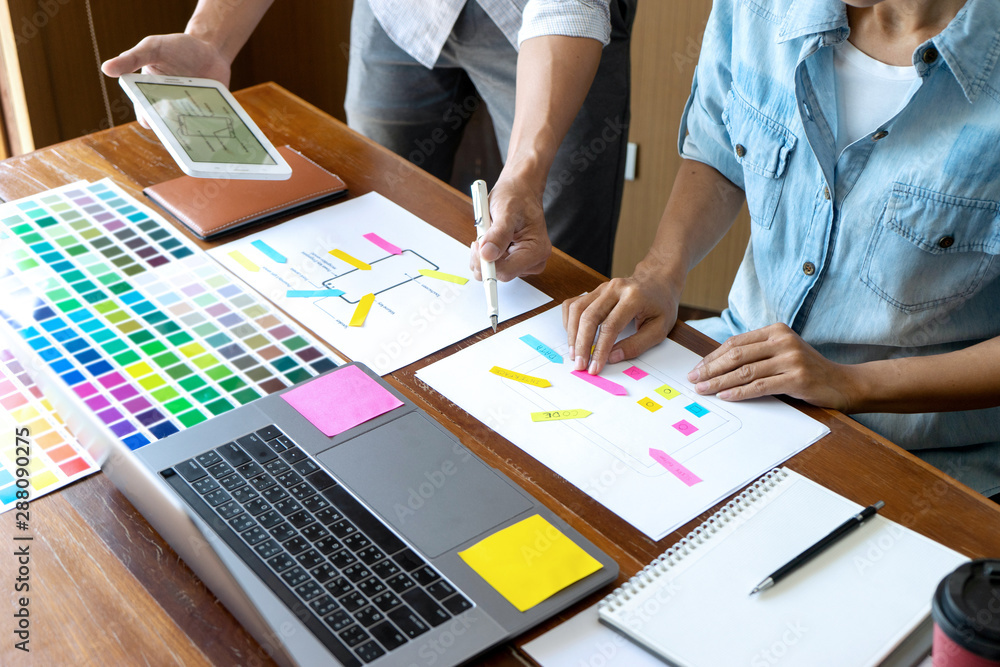 Group of young designer working in the office to design a new product, use color chart and computer laptop for new smartphone design concept Group of young designer working in the office to design a new product, use color chart and computer laptop for new smartphone design concept