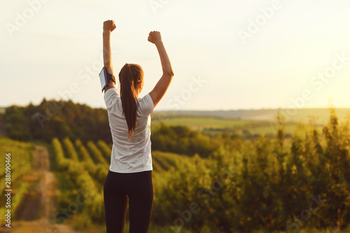 Girl raised her hands up at a training on the nature on the morning.
