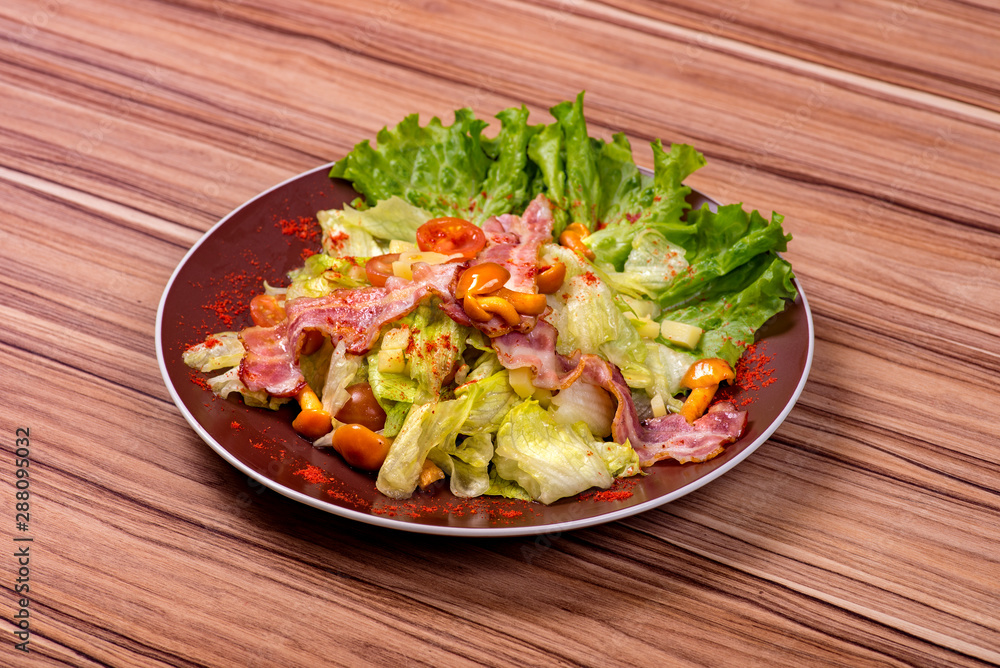 Salad with toasted bacon slices, canned mushrooms under olive oil in a dish on a wooden table. Salad with toasted bacon slices, canned mushrooms under olive oil in a dish on a wooden table.