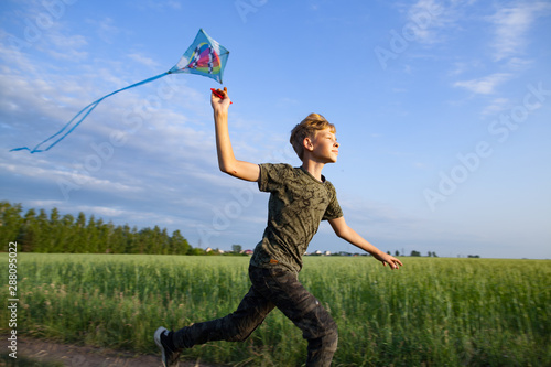 A child plays with a kite at sunset in the field.