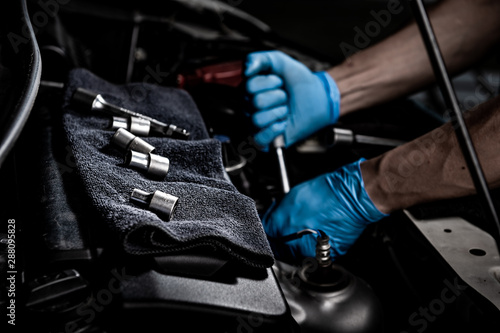 Engine check concept. Close up hand doing car service. Tight nut by socket block. © candyhalls