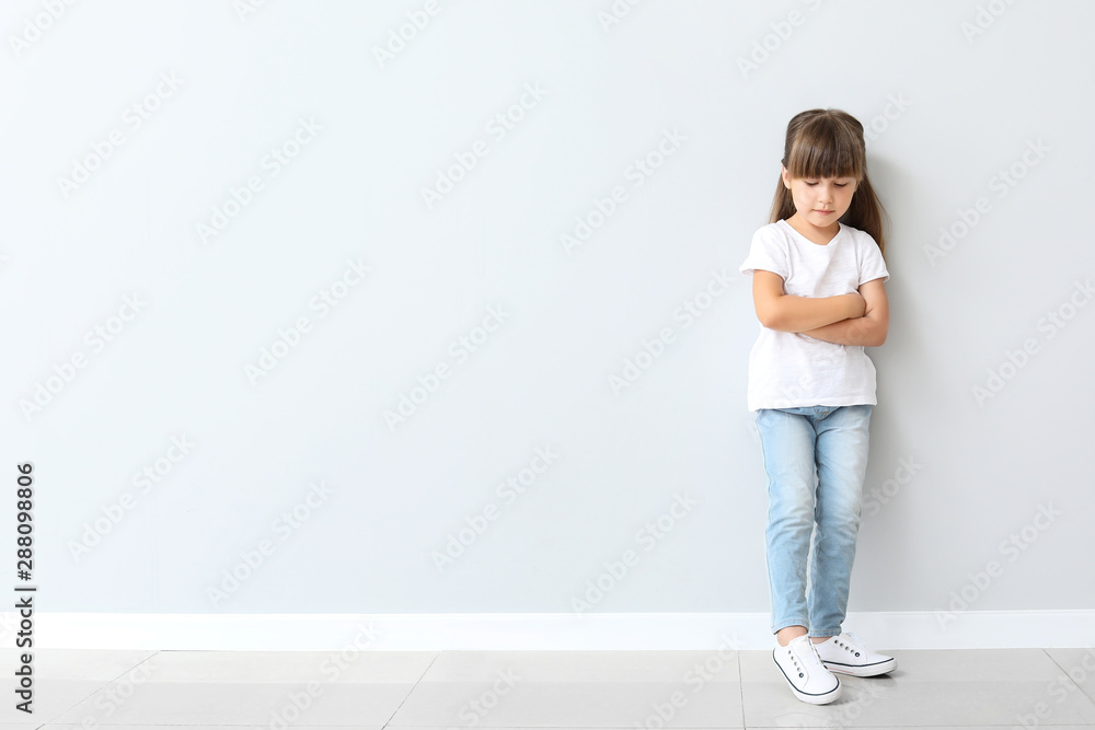 Little girl in stylish t-shirt near light wall Little girl in stylish t-shirt near light wall