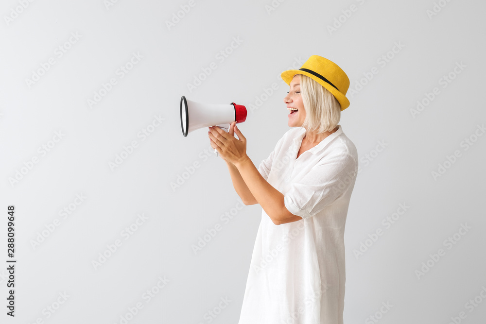 Mature woman with megaphone on light background Mature woman with megaphone on light background