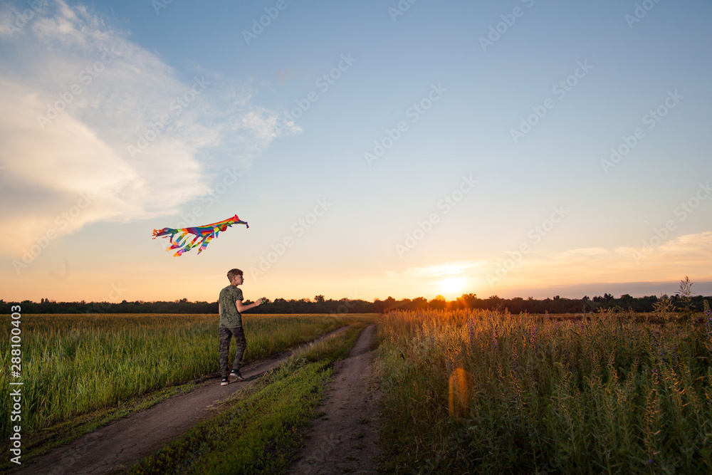A child plays with a kite at sunset in the field. A child plays with a kite at sunset in the field.