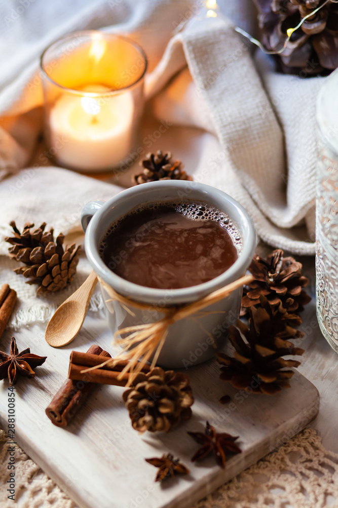 Christmas party rustic decor: grey metal mug with hot chocolate served on wooden board. Candle and delicate lamp, cones, anise stars and cinnamon sticks as decor. Cozy home atmosphere, family time Christmas party rustic decor: grey metal mug with hot chocolate served on wooden board. Candle and delicate lamp, cones, anise stars and cinnamon sticks as decor. Cozy home atmosphere, family time