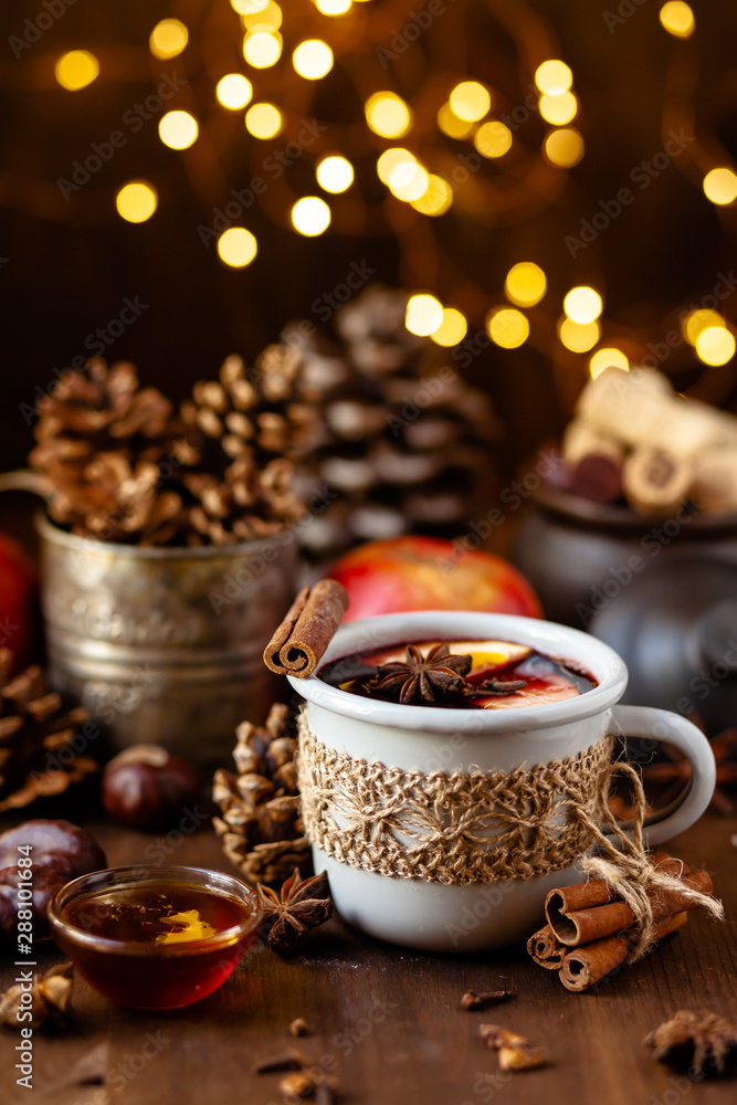 Cozy time at home with a metal mug of hot mulled wine. Autumn, warm clothes, natural ingredients, spice, fruit and honey. Corkscrew to open wine. Rustic decor, festive mood