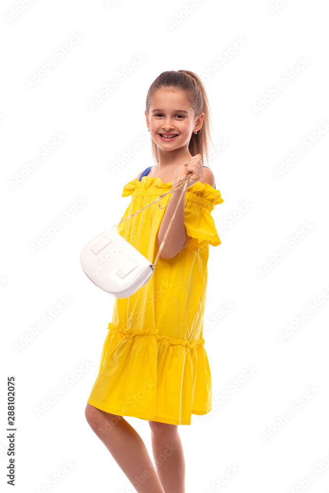 Studio shot of a little smiling girl with bag wearing yellow sundress , isolated Studio shot of a little smiling girl with bag wearing yellow sundress , isolated