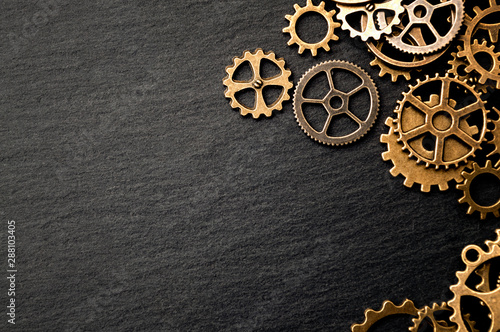 Steampunk accessories and old technology conceptual idea with border made of a group brass cog wheels on dark texture background with copy space © Victor Moussa