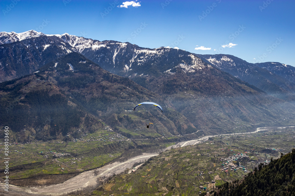 Fototapeta premium Paragliding in snow cap mountains of himalayas