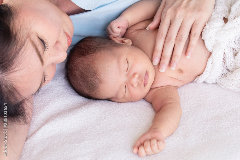 Asian beautiful mother hug adorable newborn baby 0-1 month sleep with comfortable safe in bed together at home Asian beautiful mother hug adorable newborn baby 0-1 month sleep with comfortable safe in bed together at home