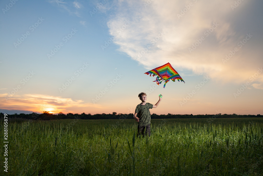 A child plays with a kite at sunset in the field. A child plays with a kite at sunset in the field.