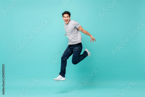 Energetic happy young Asian man in casual clothes jumping