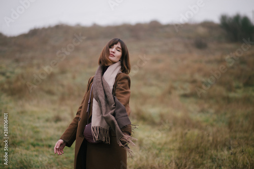 Woman in brown stylish cashmere coat posing on autumn background.