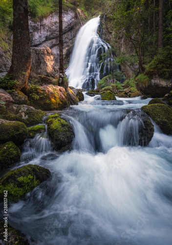 Scenic waterfall landscape with green moos stones and flowing river at beautiful summer day in Gollinger, Austria.