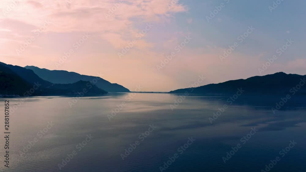 Aerial flight backwards from the ocean over the pier of Marmaris with yachts, sailing boats and castle on the shore.