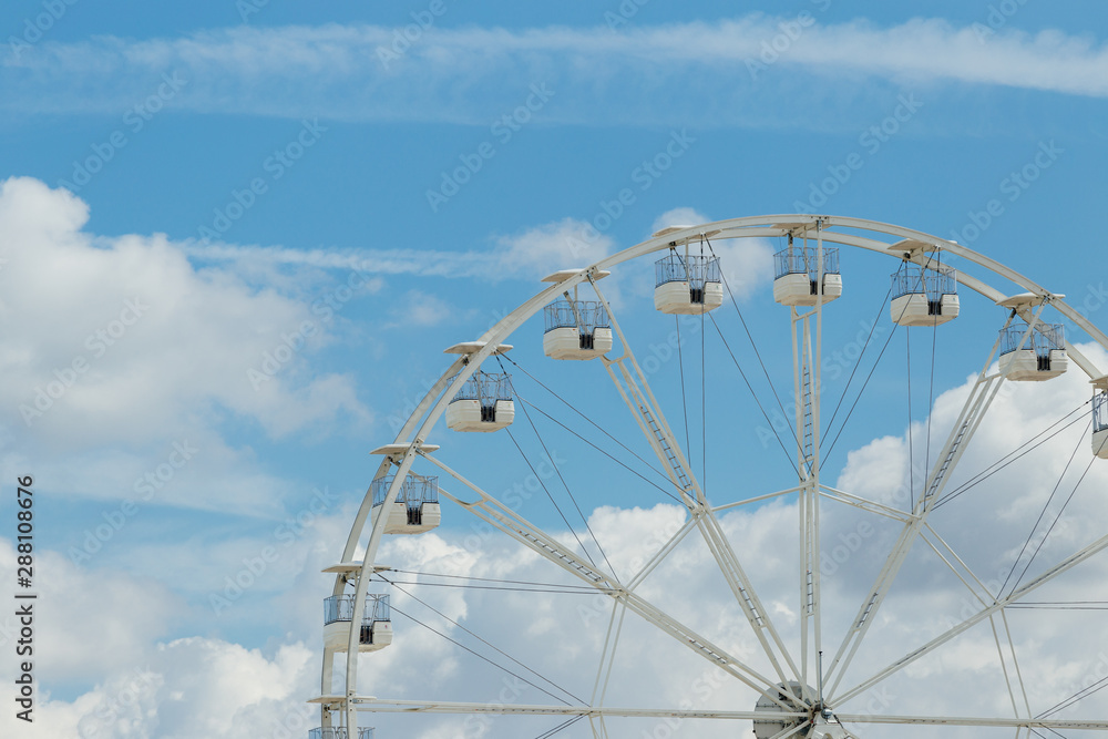 Ferris wheel on the blue cloudy sky. Background concept of happy holidays time. Ferris wheel on the blue cloudy sky. Background concept of happy holidays time.