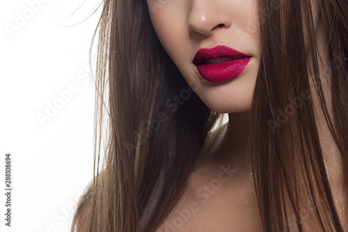 Beauty closeup of women full red lips with shiny skin and long hair. Facial skin care in a spa salon or cosmetology and a fashionable pink lip gloss. Evening makeup