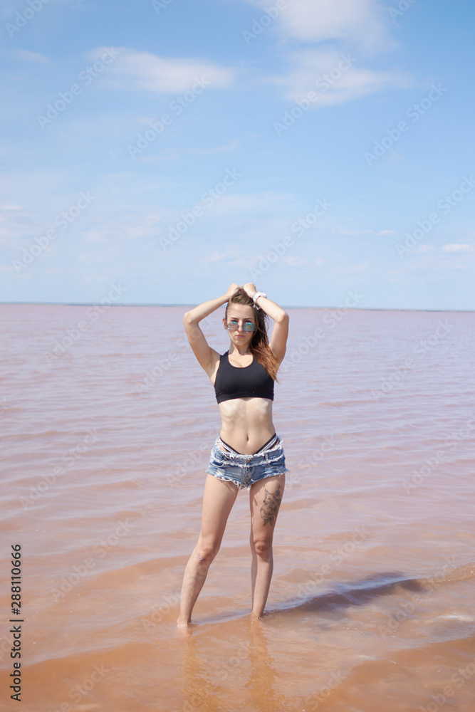 Young sexy fit curvy woman posing near the pink lake