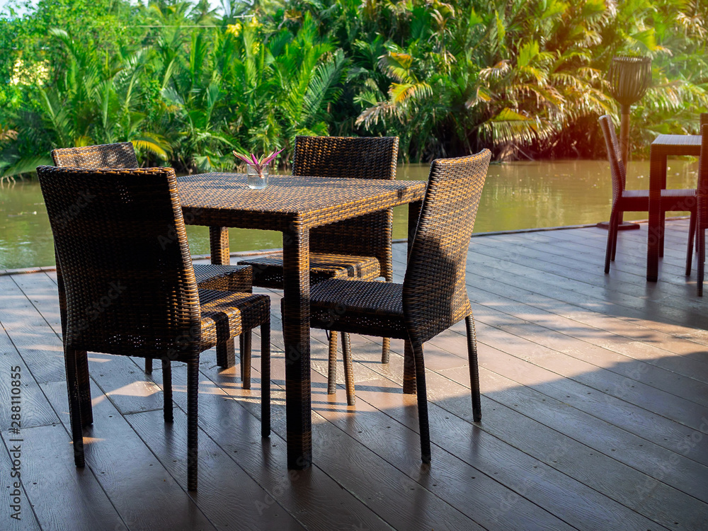 Rattan dining table furniture set on wooden terrace.