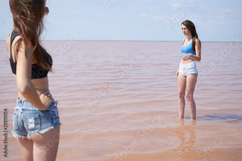 Sexy young woman posing near the pink lake