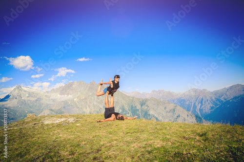 Giovane coppia pratica acroyoga e yoga all'aperto in montagna