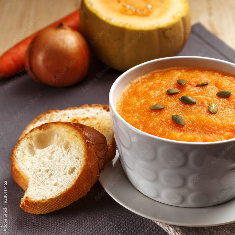 Pumpkin soup with pumpkin seeds in a white plate. Two croutons near the soup. Pumpkin soup with pumpkin seeds in a white plate. Two croutons near the soup.