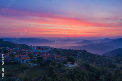 Sunrise in the mountains. The Golden-pink sky, mountains, morning fog and a small village on the mountainside are depicted. Istria, Croatia. The view from the top. Copy space. © ROMAN DZIUBALO